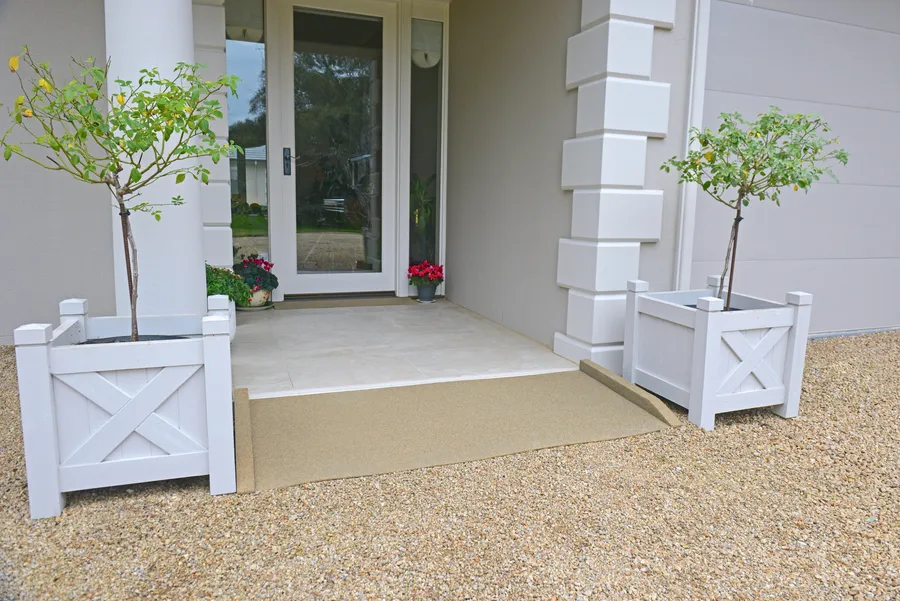 Sand coloured recycled rubber ramp at a rendered home entry with white planter boxes