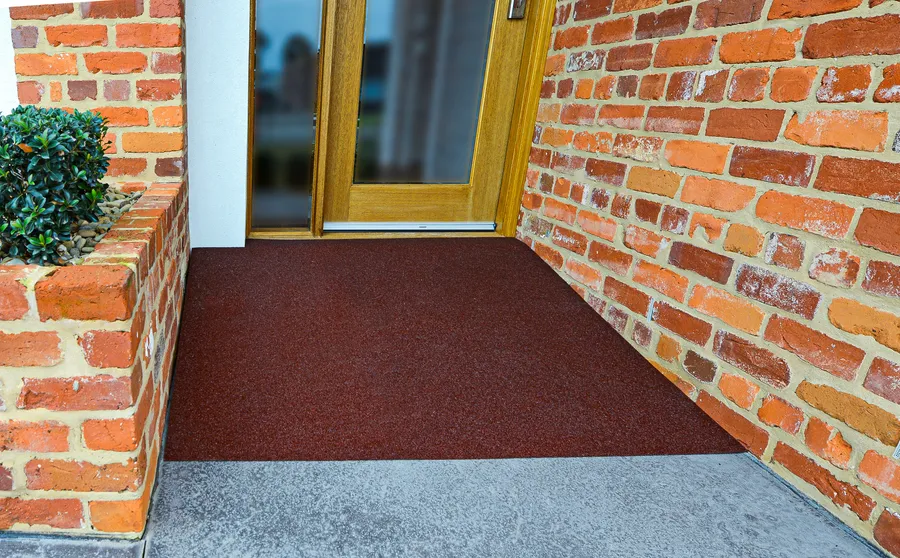 Brick red threshold surface at a timber door between red brick walls